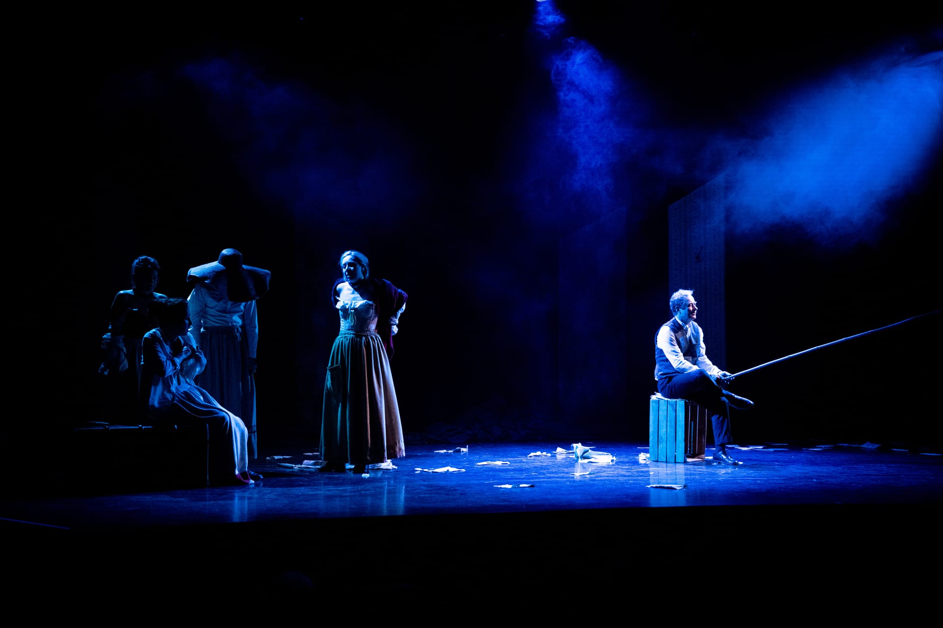 Les femmes face à un homme assis, lumière bleue, scène finale